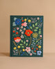 The Strawberry Fields Embroidered Sketchbook is a dark green hardcover journal with colorful floral, leaf, strawberry, and berry embroidery on the cover, displayed against a plain beige background.