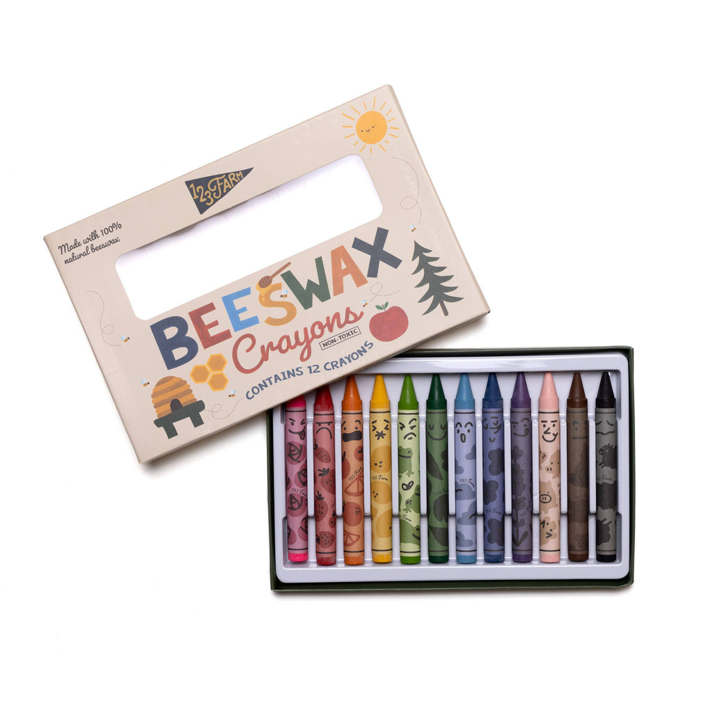 A box of 12 Beeswax Crayons – Non-Toxic, each with cute faces, sits in open packaging featuring playful natural illustrations—an eco-friendly choice for colorful creativity.