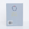The light blue back cover of the A Christmas Carol | Collector's Edition | Hardcover Book features a wreath with a red bow and gold text: “I will honour Christmas in my heart and try to keep it all the year.” Barcode is at the bottom.