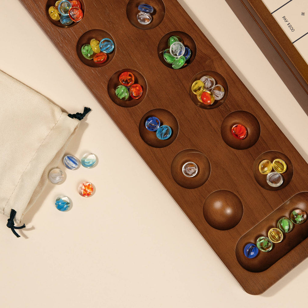 Part of the 3-in-1 Game Collection: Monopoly, Sorry & Mancala, this set features vibrant marbles on a wooden mancala board, with a cream drawstring bag for storage—a timeless classic perfect for any game cabinet.
