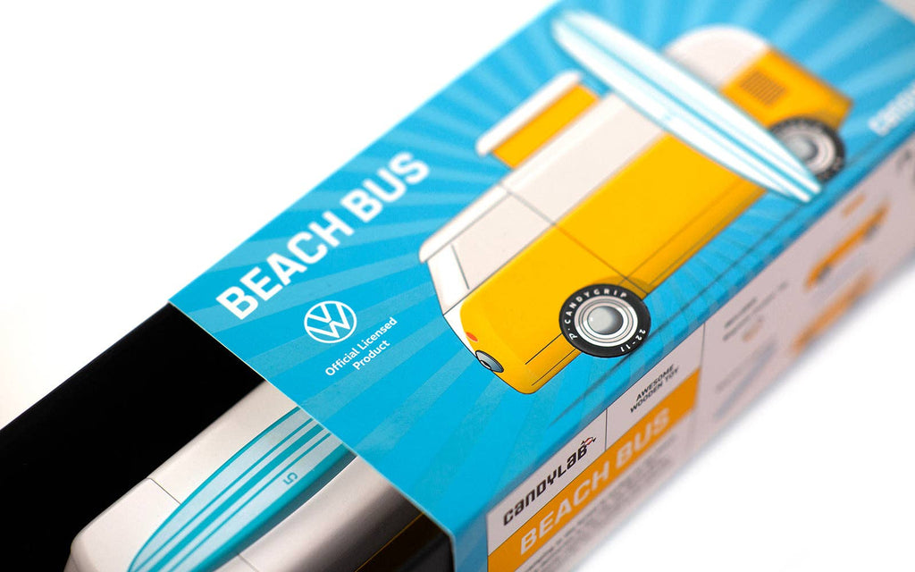 Close-up of a product box labeled "VW Beach Bus Sunset," featuring a yellow and white van with a surfboard on top. The packaging displays the Volkswagen logo, highlighting this Volkswagen Type 2 as an official licensed product.