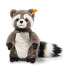 The Steiff Pedro Raccoon 9" is a plush toy with brown and white fur, a white belly, black paws, a fluffy striped tail, and a yellow tag in one ear, shown sitting upright against a white background.