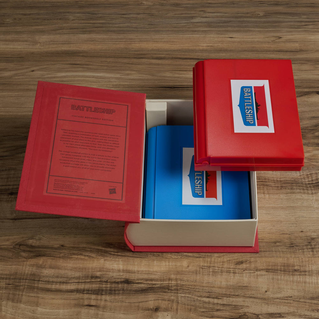 An open Board Book: Battleship Vintage Bookshelf Edition rests on a wooden surface, showing two blue game boards inside. The box lid features the Battleship logo, evoking the classic naval strategy game.