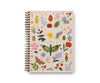 The Curio Spiral Notebook is a spiral-bound softcover with a cream cover featuring colorful florals, insects, and strawberries. "Rifle Paper Co." is printed in gold at the center. It includes ruled pages for easy writing.