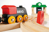 A close-up of the BRIO World Train Set Classic Figure 8 Set shows a wooden toy train with red and black colors, yellow wheels, and a red bumper on its track. A small green and white station building appears in the background.