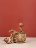 Two Spring Copenhagen The Snake wooden figurines with painted eyes and tongues are displayed in and beside a woven basket against a muted terracotta background—one coiled on the surface, the other rising from the basket—a unique spiritual gift.