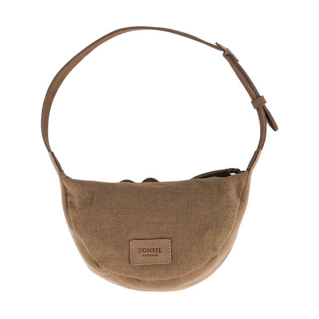 The Donsje Leather Talei Bumbag Purse - Sloth is a beige crossbody bag for kids, featuring a rounded shape, adjustable strap, and a "DONSJE AMSTERDAM" patch on the front. It is shown against a plain white background.