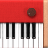 Close-up of the Loog Piano's velocity-sensitive keys, red textured panel, dark wood knob with white dot, and light wood trim—premium features for musician-grade piano sound.