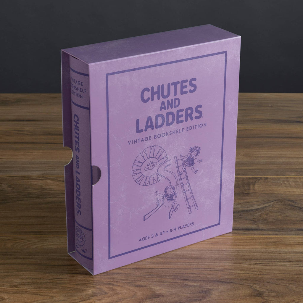 A purple "Chutes and Ladders Vintage Bookshelf Edition" box rests on a wooden table. This classic board game, for ages 3+ and 2-4 players, features simple line drawings of kids on ladders and chutes.