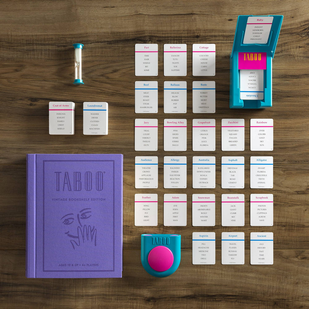The Board Game: Taboo Vintage Bookshelf Edition is displayed on a wooden table, including a purple book-shaped box, timer, buzzer, card holder, and neatly arranged game cards.