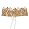The Crown - Gold Sequins features a sparkly, scalloped gold design covered in sequins, lined with soft fabric. Created by Luciole et Petit Pois in France, it has white ribbon ties at the back for a secure fit.
