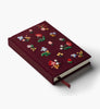 The Gracie Mini Embroidered Journal, closed and maroon with colorful flowers on the cover, rests on a white background. A matching ribbon bookmark peeks out, hinting at its blank unlined pages inside.