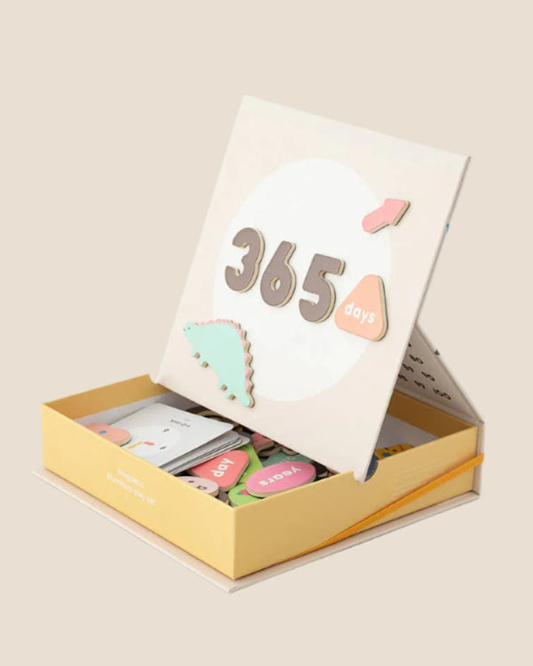 The Magnetic Number Play Set comes in a pastel box with a propped-up lid that says "365 days" and includes alphabet cards, magnet puzzles, and colorful wooden toys neatly arranged inside.