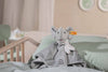 The “My First Steiff” Ellie Elephant Security Blanket Baby Toy, 10 Inches, with a striped scarf and embroidered blanket, rests on a mint-green bed in a softly lit nursery.
