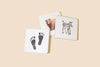 The Baby's Tummy Time Book Box Set features three square white board books with high-contrast black artwork—a footprint, a bear, and a zebra—on a light beige background to support your baby’s visual milestones.