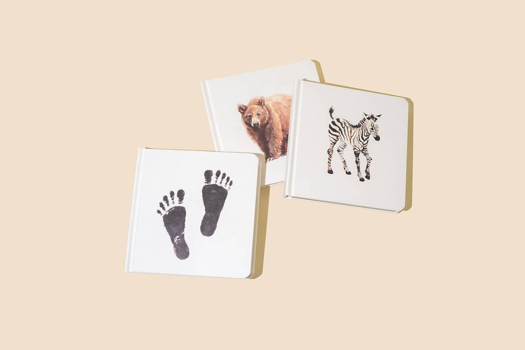 The Baby's Tummy Time Book Box Set features three square white board books with high-contrast black artwork—a footprint, a bear, and a zebra—on a light beige background to support your baby’s visual milestones.