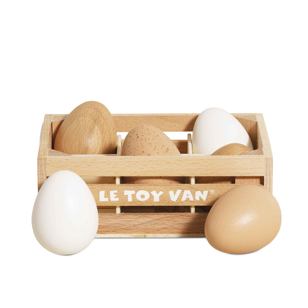 The Farm Eggs Wooden Market Crate holds six pretend play wooden farm eggs—some smooth and painted, others natural wood—in assorted brown and white shades.