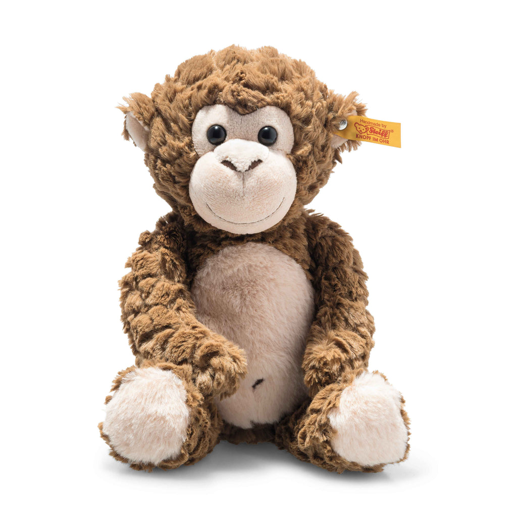 The Bodo Monkey Plush Stuffed Toy, 12 Inches, has a light beige face, belly, hands, and feet, large round eyes, a yellow tag in its left ear, and sits upright against a white background.