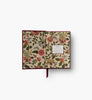 The Gracie Mini Embroidered Journal is an open hardcover with floral and butterfly inner covers, blank unlined pages, a labeled "Journal" insert on the right, and a red ribbon bookmark hanging from the center.