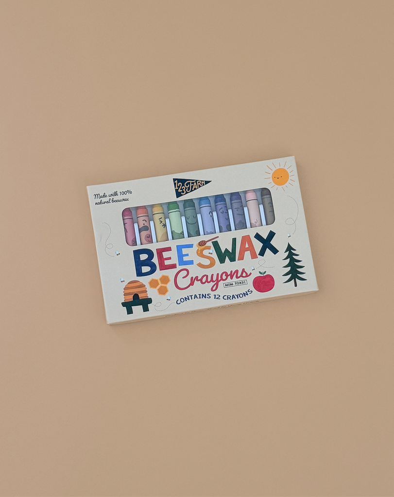 A box of 12 Beeswax Crayons – Non-Toxic on a beige background, with packaging showing sun, bee, tree, and beehive illustrations and the text “Made with 100% natural beeswax.” Safe, eco-friendly crayons for creative kids.