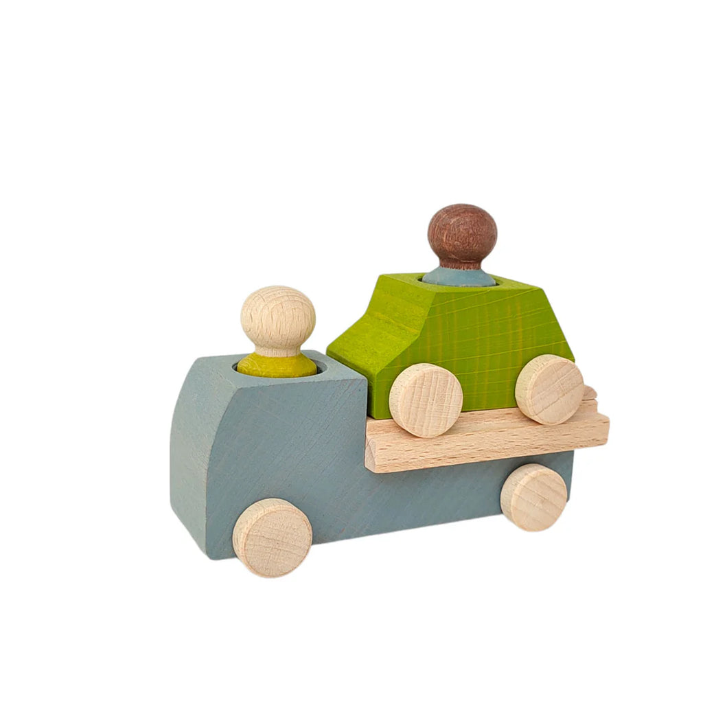 The Lubulona Wooden Tow Truck - Grey features a minimalist design with grey and natural wood tones, includes a small green car and two peg figures in yellow and brown, making it perfect for small-world play.