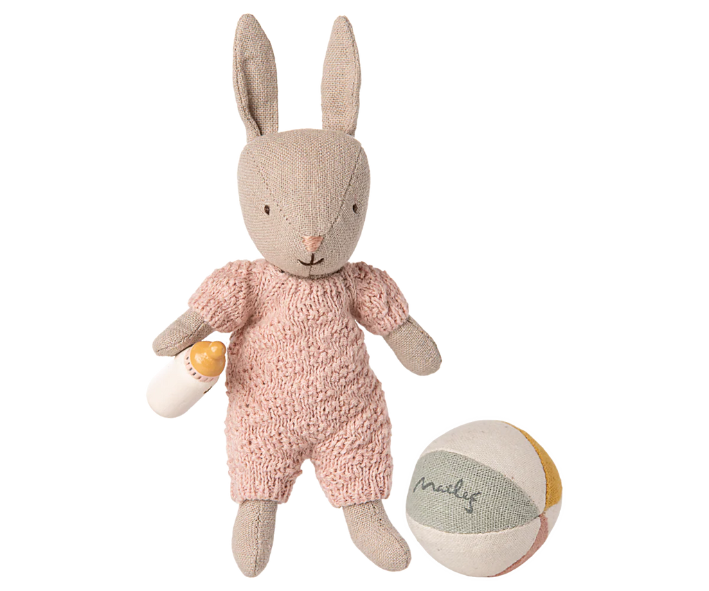 The PRE-ORDER: Rabbit Set, Micro - Sand - Rose (Ships Early November) features a soft bunny in a pink knitted outfit with a toy baby bottle and pastel "Maileg" ball—perfect for collectors and imaginative storytelling.