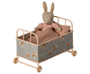 A PRE-ORDER: Cot Bed, Micro - Powder (ships early October) displays a stuffed rabbit in a pink dress, resting with a floral-patterned frame and pink-and-white checkered blanket and pillow.