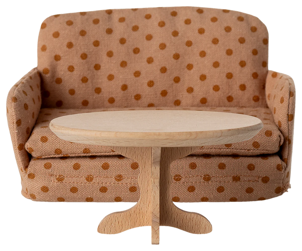 A PRE-ORDER: Oval Coffee Table, Mouse - Nature (Estimated Ship Date: Early October) from SuitCasa sits in front of a miniature beige couch with brown polka dots.
