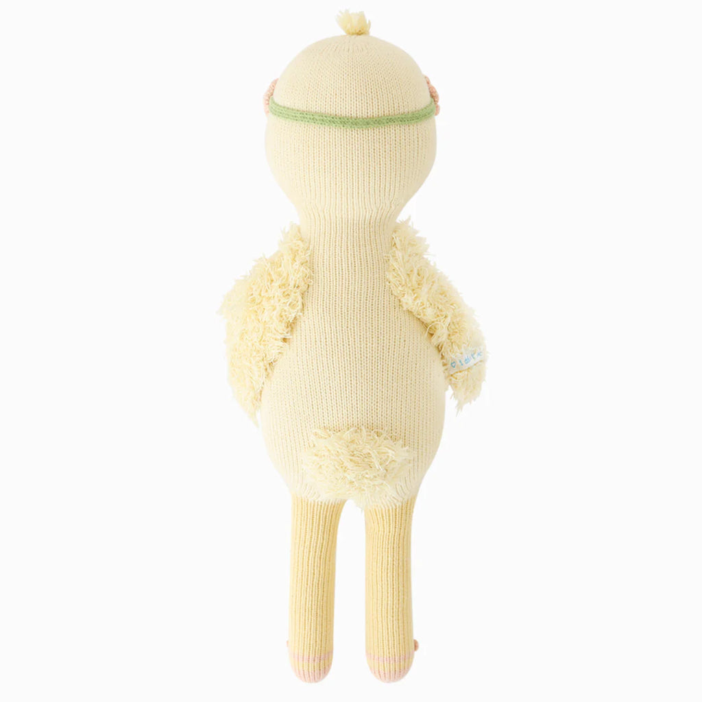 The Cuddle + Kind Duckling is a yellow, knitted plush toy shown from the back, standing upright with textured wings, long legs, a round tail, and a green head stripe—expertly crafted from 100% cotton yarn.