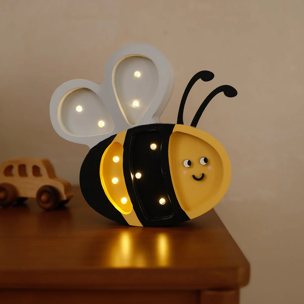 The Handmade Wooden Mini Lamp - Happy Bee features a smiling face and glowing bulbs on its wings and body. With black antennae, it’s perfect as a children’s night light or charming kids’ room decor. Sits nicely on any wooden surface.