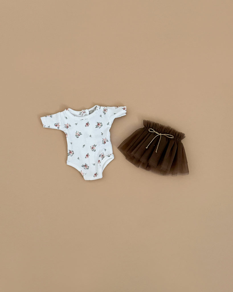 The Minikane Doll Clothing Josepha Set features a pink flower bodysuit and a brown tulle tutu with a gold bow, designed for Minikane dolls and shown on a plain beige background.