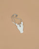 The Donsje Leather Blinc Purse - Unicorn is a small white purse with a silver glittery horn and adjustable leather strap, shown on a plain light brown background.