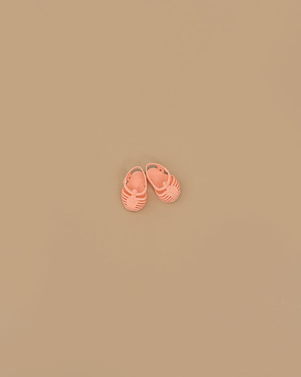 A pair of Minikane Beach Sandals in peach are placed side by side on a plain beige background.
