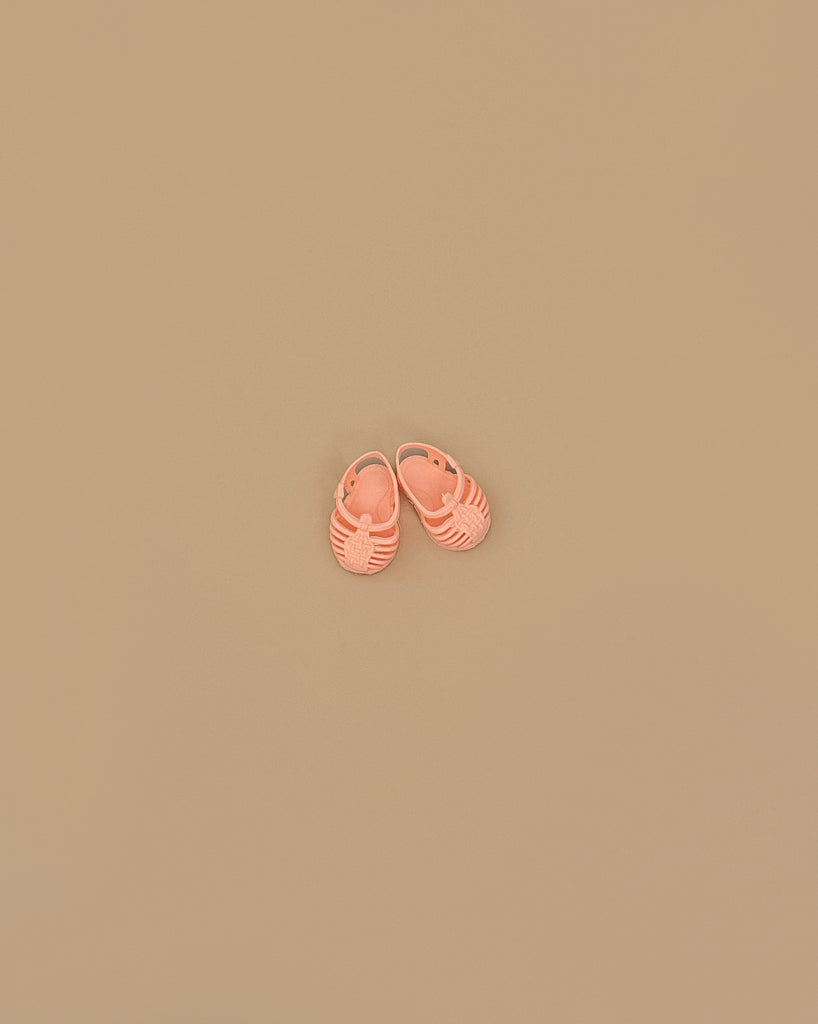 A pair of Minikane Beach Sandals in peach are placed side by side on a plain beige background.