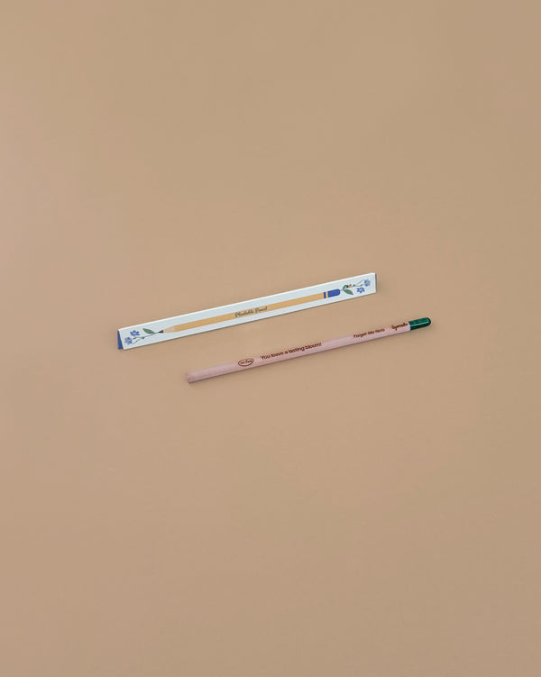 A pregnancy test and a Tomatoes Plantable Pencil – Eco-Friendly with a green eraser are placed on a plain beige surface. The pencil, ideal for growing cherry tomatoes, sits below the pregnancy test.