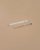 A pregnancy test and a Tomatoes Plantable Pencil – Eco-Friendly with a green eraser are placed on a plain beige surface. The pencil, ideal for growing cherry tomatoes, sits below the pregnancy test.