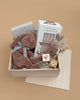 The Newborn Gift Set includes two Maileg Plush Sleeping Bunnies, "Our Very Little Library" book, a floral envelope, Watercolor ABC Block (D), a small box, and dried flowers, beautifully arranged against a beige background.