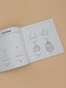 An open copy of "All the Things: How To Draw Books For Kids" rests on a beige surface, displaying step-by-step cupcake drawing instructions, from basic shapes to a finished treat—ideal for simple drawing lessons.