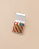 An open box of Kitpas Crayons - 6 Colors sits on a plain beige background. The six thick, non-toxic crayons have brown paper wrappers and are in a white box with red edges.