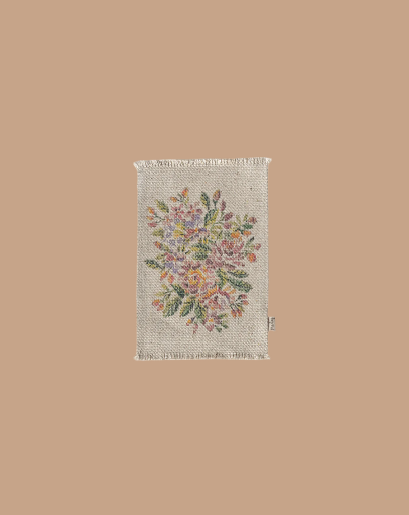 The Maileg Living Room Starter Set includes a small, rectangular beige rug with fringe edges and an embroidered floral design in pastel pink, yellow, orange, and green on a light background—perfect for decorating your mice's living room.