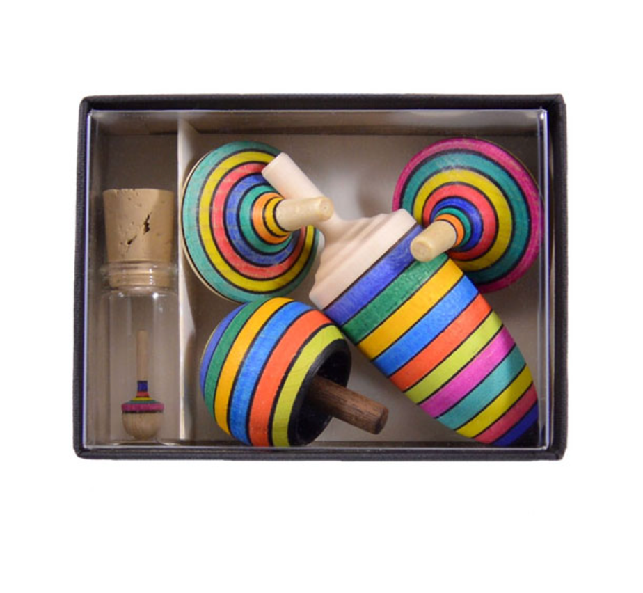 The Mader Spinning Top Champion Learning Set - Striped includes four colorful striped tops in different sizes and a small glass vial with a mini spinning top inside. Contains small parts; choking hazard—meets toy safety standards.