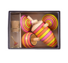 The Mader Spinning Top Champion Learning Set - Fire includes four colorful striped tops in assorted sizes and a small glass bottle with a cork lid containing a miniature top, all made to meet toy safety standards.