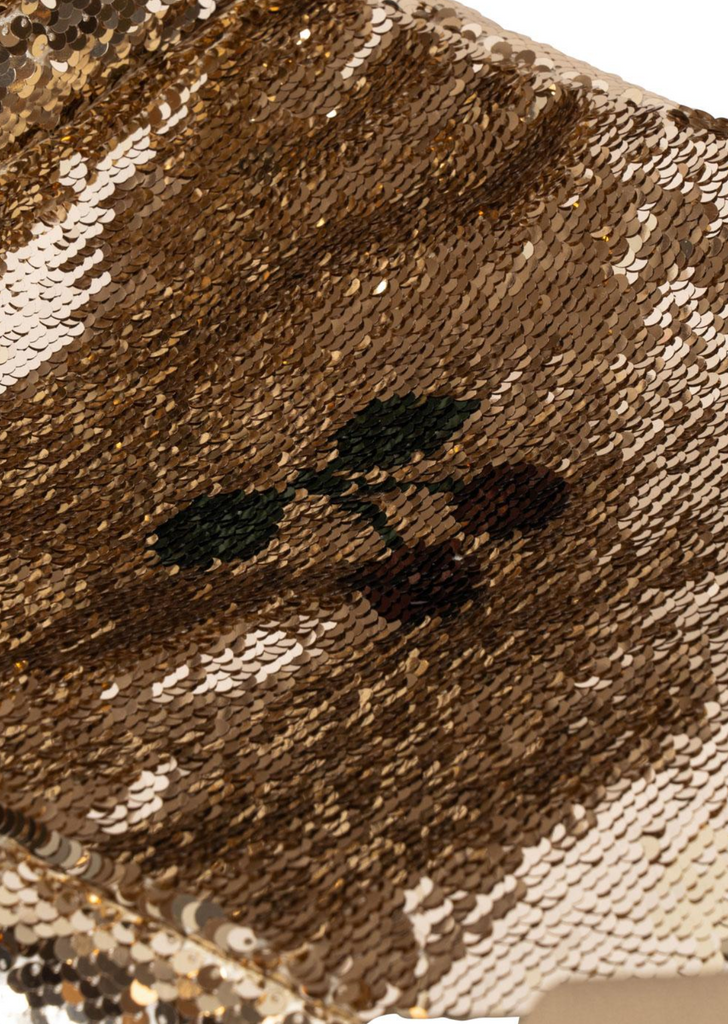 Close-up of gold sequins and a small embroidered cherry design, echoing the charming details featured on the Konges Sloejd Sparkly Doll Pram - Golden Cherry.