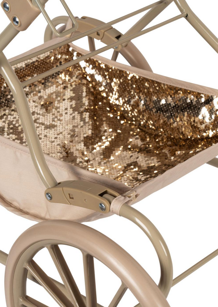 Close-up of the Konges Sloejd Sparkly Doll Pram - Golden Cherry, featuring a beige frame, large wheels, and a basket area lined with shiny gold sequined fabric for a charming vintage-inspired look.