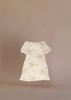 The Maileg Little Sister Bedroom Set includes a charming cream dress with short sleeves, lace trim, and a floral pattern—ideal for your Maileg Ballerina Mouse. Shown on a plain beige background.