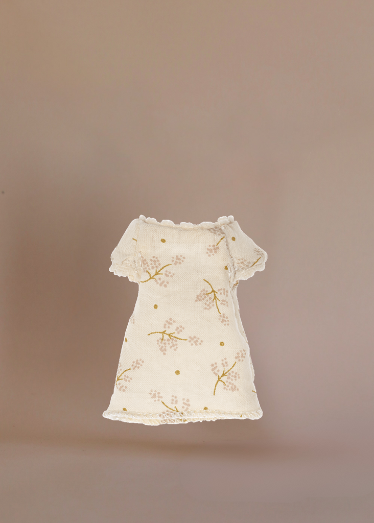 The Maileg Little Sister Bedroom Set includes a charming cream dress with short sleeves, lace trim, and a floral pattern—ideal for your Maileg Ballerina Mouse. Shown on a plain beige background.
