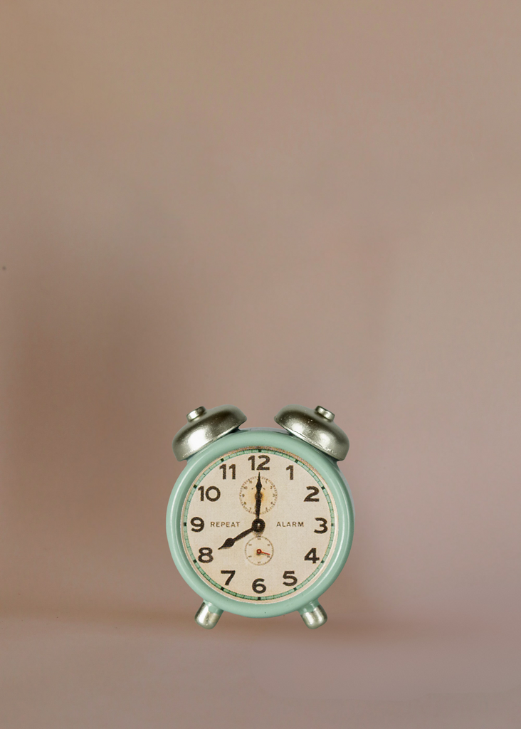 A vintage-style mint green alarm clock with silver bells stands on a plain light brown background, paired perfectly with the charming Maileg Living Room Set, showing the time as 8:00.
