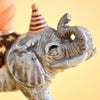 Close-up of the Elephant Cake Topper, a fine porcelain figurine in a striped party hat against a yellow background. Its detailed features offer a whimsical, festive touch—ideal as an heirloom-quality collectible keepsake.