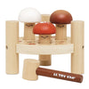 The Woodland Mushroom Hammer Game includes three smiling, mushroom-shaped pegs, a round stand with four posts, and a mallet labeled "LE TOY VAN"—ideal for building fine motor skills.