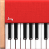 Close-up of the Loog Piano, a portable digital instrument with eight velocity-sensitive black and white keys, red top panel, wooden sides, and the white "loog" logo displayed on its red surface.